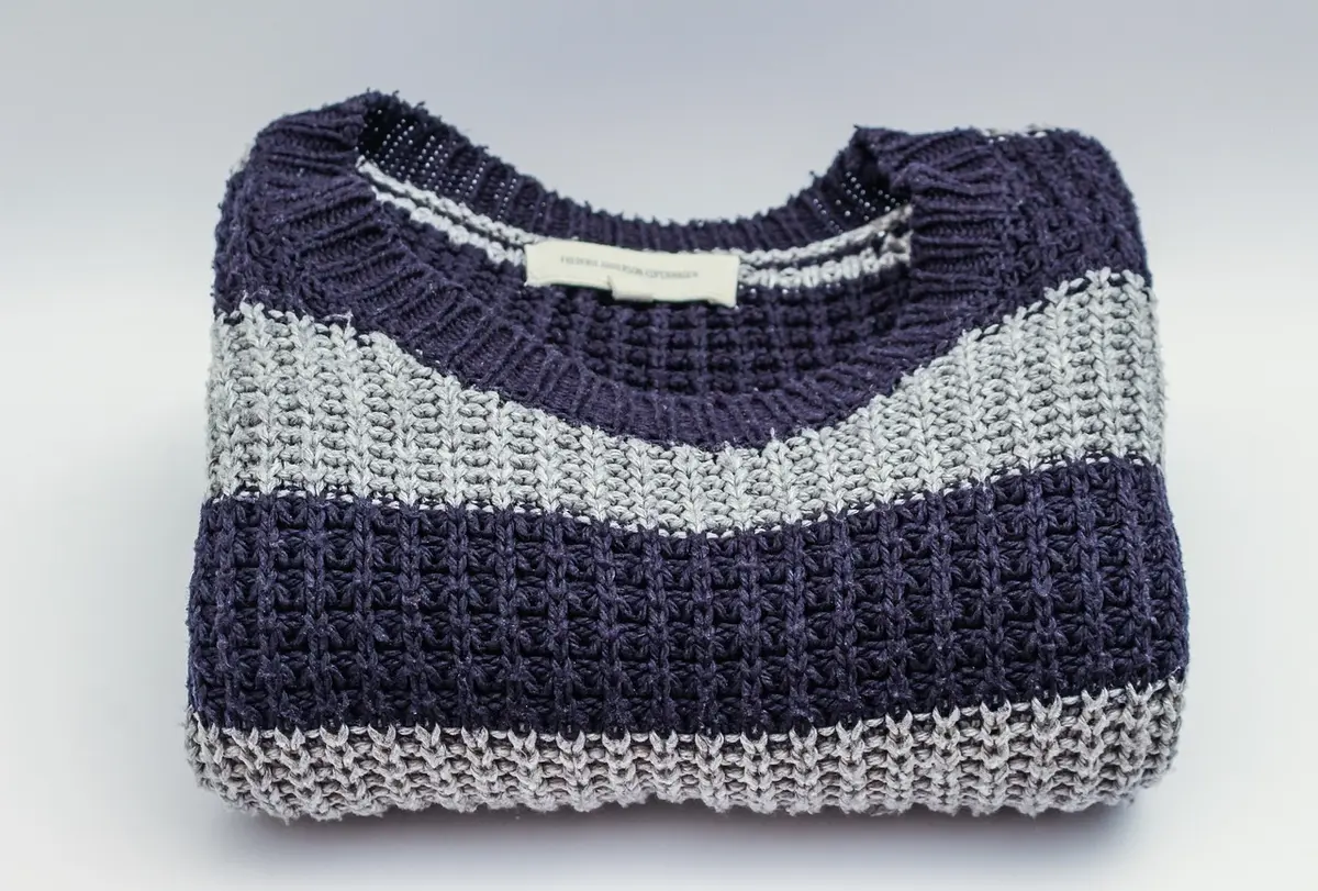 Pièces de base neutres pliées et empilées : pull, chemise, jean, veste