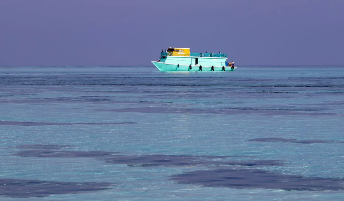 Bateau à longue queue naviguant sur des eaux turquoises vers des îles tropicales avec des palmiers