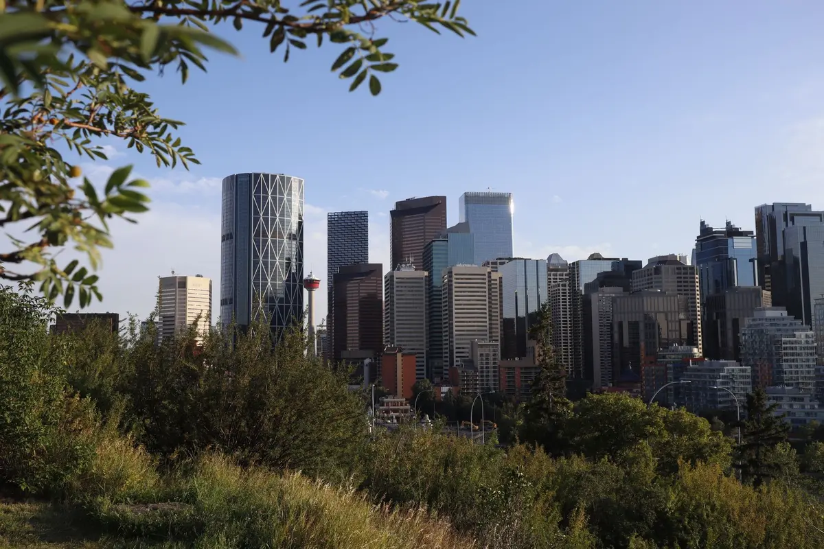 Vue panoramique d'une silhouette face aux gratte-ciel de Calgary et aux montagnes Rocheuses enneigées en arrière-plan
