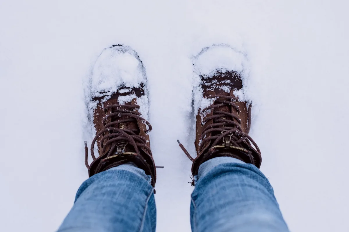 Paire de bottes de neige isolées posées dans la neige fraîche avec des cristaux de givre
