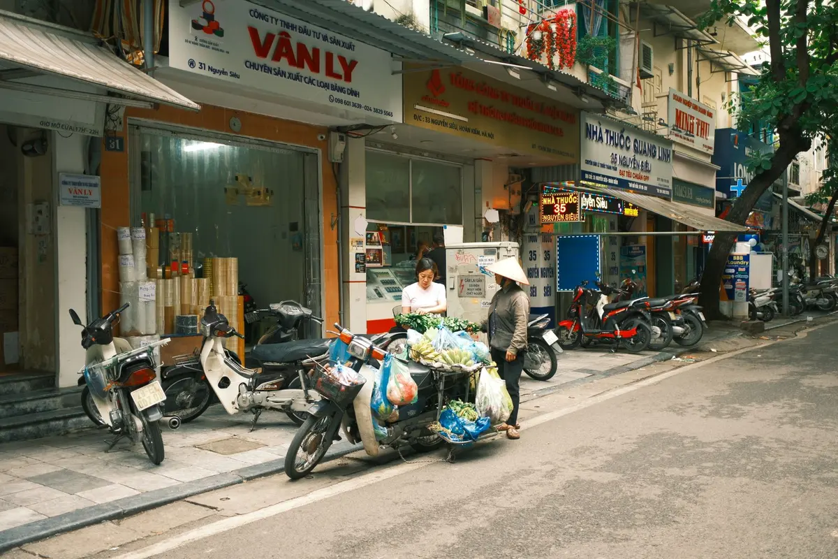 Marché vietnamien avec étals colorés de fruits tropicaux, épices et artisanat sous des auvents