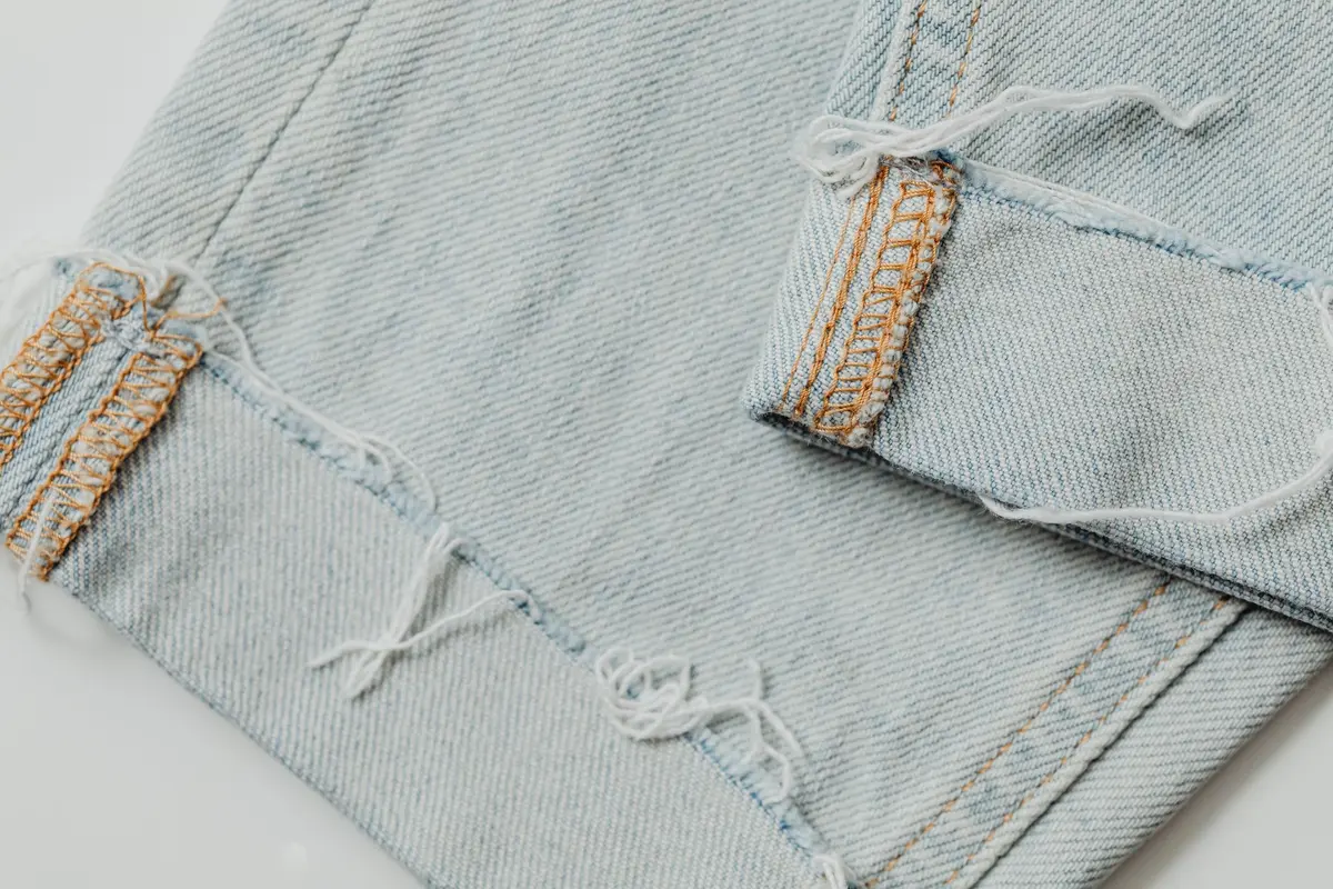 Détail rapproché d'un ourlet brut effiloché sur du tissu denim