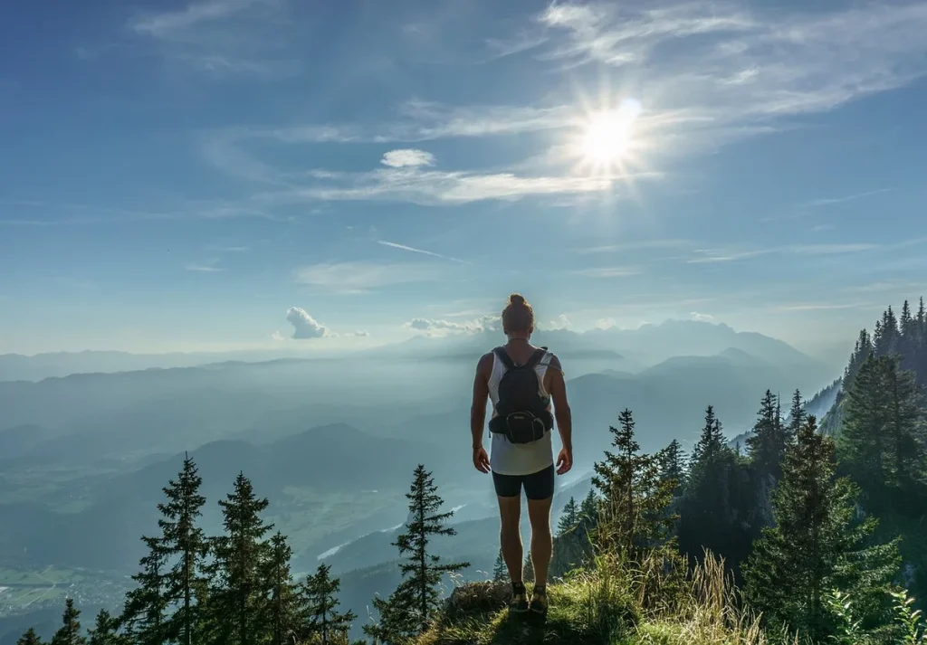 Randonneur en silhouette sur un sentier de montagne au lever du soleil avec des pics enneigés en arrière-plan