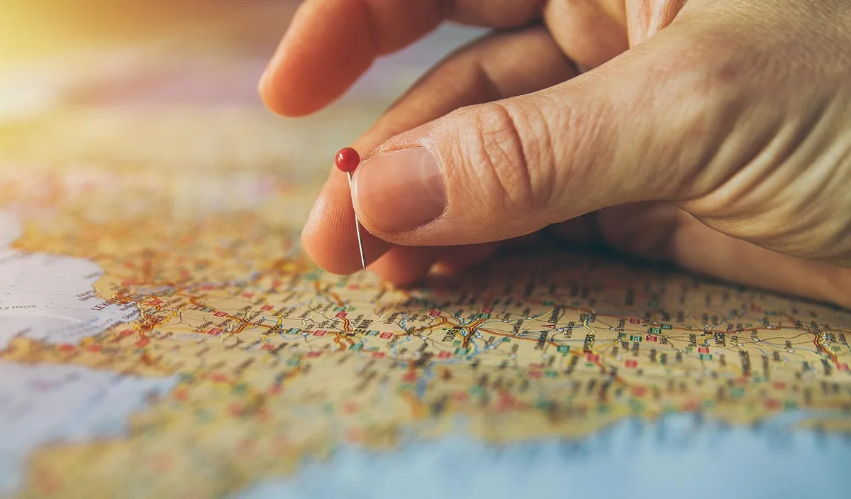 Voyageur préparant son itinéraire avec carte, ordinateur portable et documents de voyage sur un bureau