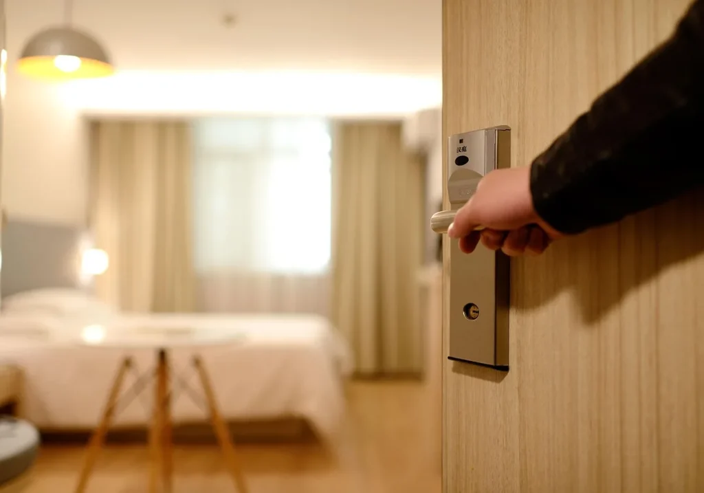 Chambre d'hôtel en plein jour avec valise ouverte et petit coffre portable fixé sur un bureau