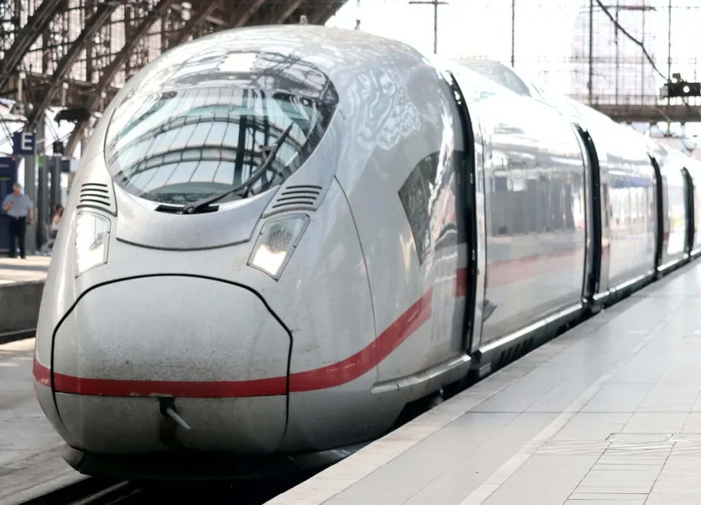 Sac polochon à roulettes posé sur un banc dans une gare en plein jour