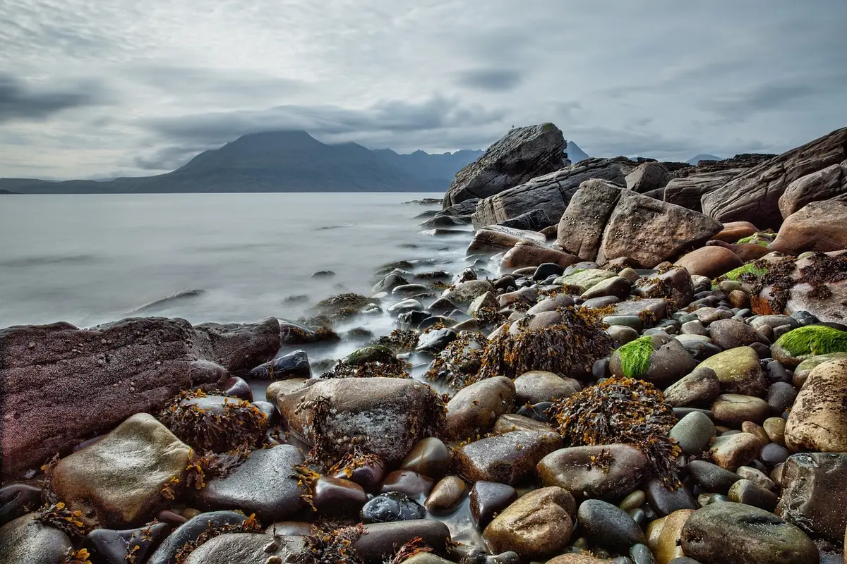 Chaussures d'eau posées sur du sable près de rochers, illustrant plage et rochers