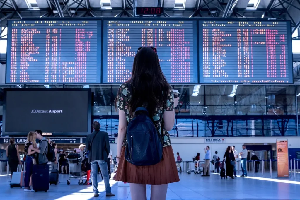 Plusieurs valises cabine alignées près d'un gabarit de contrôle à l'aéroport, mains anonymes mesurant une valise