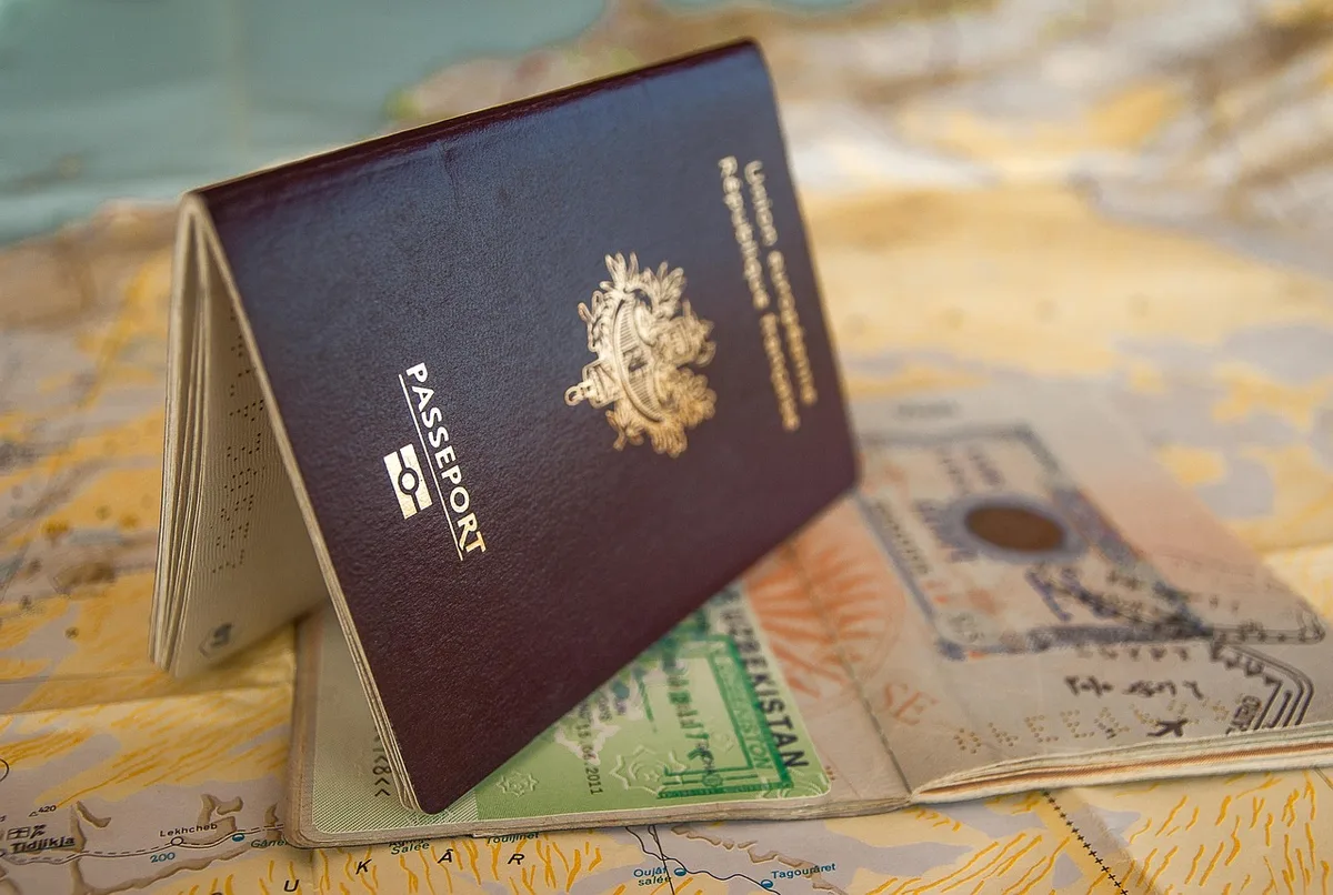 Voyageur consultant son passeport et un formulaire IMUGA dans un hall d'arrivée