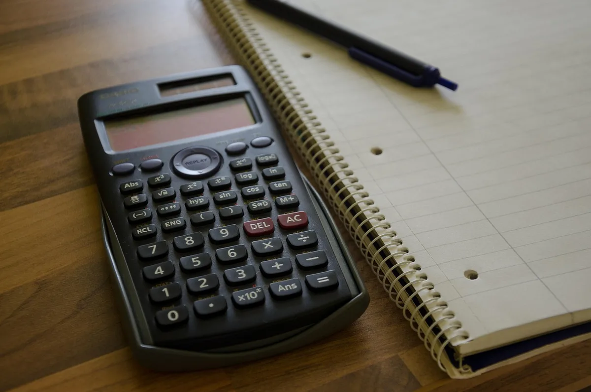 Carnet, calculatrice et carte bancaire sur un bureau pendant une session de calcul