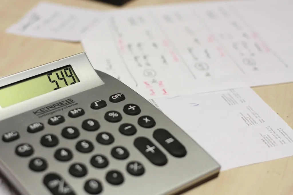 Mains sur un bureau lumineux avec calculatrice, carnet de budget et cartes empilées