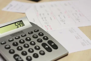 Mains sur un bureau lumineux avec calculatrice, carnet de budget et cartes empilées