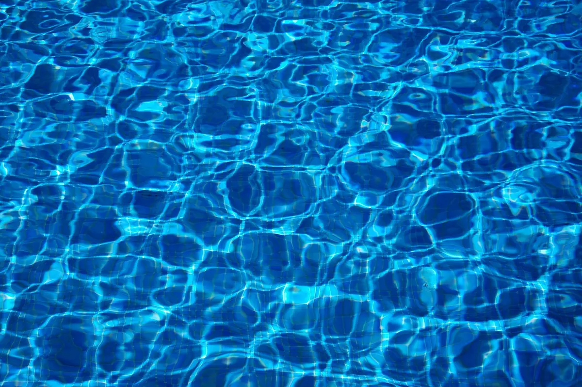 Personne rinçant une bouée à l'eau douce au bord d'une piscine en plein jour