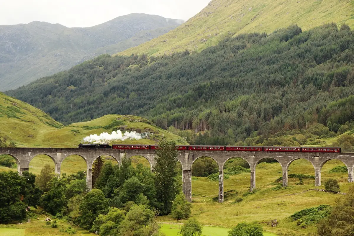 Le train montant vers le col sur un viaduc en bois, panorama alpin